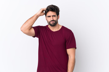 Young handsome man with beard over isolated white background having doubts while scratching head