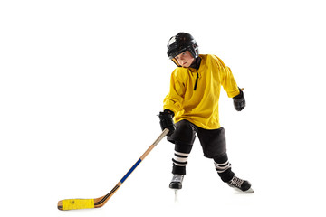 Little hockey player with the stick on ice court and white studio background. Sportsboy wearing equipment and helmet practicing, training. Concept of sport, healthy lifestyle, motion, movement, action