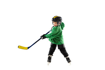 Little hockey player with the stick on ice court, white studio background. Sportsboy wearing equipment and helmet, practicing, training. Concept of sport, healthy lifestyle, motion, movement, action.