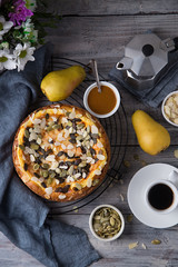 Autumn homemade pear pie with pumpkin seeds and almond petals on wood grey table and coffee cup top view