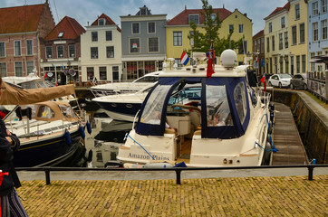 Fototapeta na wymiar Goes, the netherlands, august 2019. View of the small and pretty harbor. It creeps between the historic houses of the center, along the piers trees and lampposts with planters.
