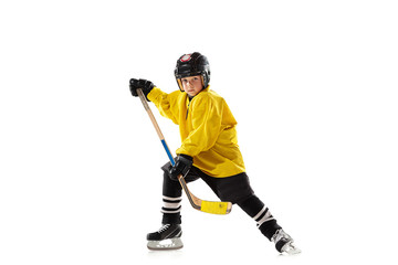 Little hockey player with the stick on ice court and white studio background. Sportsboy wearing equipment and helmet practicing, training. Concept of sport, healthy lifestyle, motion, movement, action