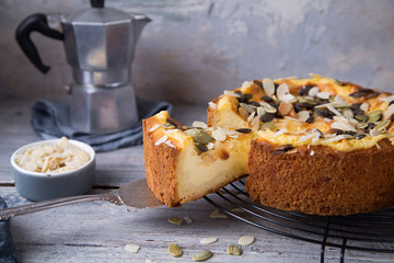 Autumn homemade pear pie with pumpkin seeds and almond petals on wood grey table and coffee cup
