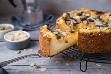Autumn homemade pear pie with pumpkin seeds and almond petals on wood grey table and coffee cup
