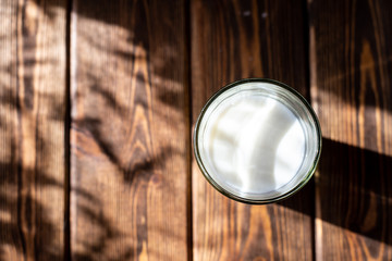 glass of milk on a wooden table. dark background, bright contrasting sun