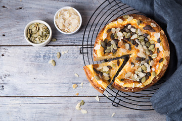Pears and cheese pie with bowl of caramel, pumpkin seeds and almond petals. Top view. Copy space flat lay
