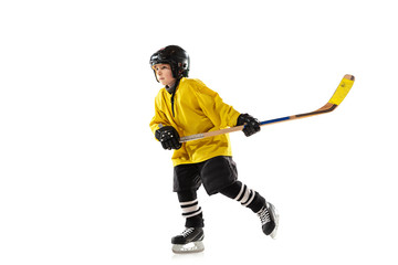 Fototapeta premium Little hockey player with the stick on ice court and white studio background. Sportsboy wearing equipment and helmet practicing, training. Concept of sport, healthy lifestyle, motion, movement, action