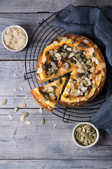 Pears and cheese pie with bowl of caramel, pumpkin seeds and almond petals. Top view. Copy space flat lay