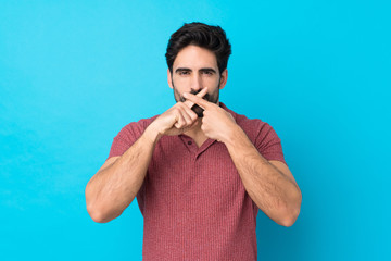 Naklejka premium Young handsome man with beard over isolated blue background showing a sign of silence gesture