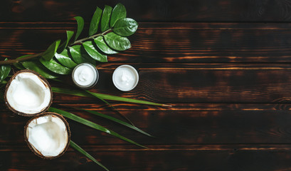 Coconut and moisturizer with green plants on an old wooden background with top view and copy space. Natural cosmetics FLATLAY.