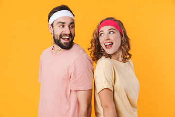 Portrait of athletic young couple smiling and standing back to back