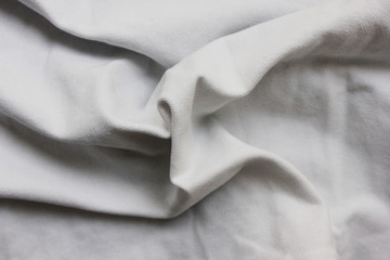 Wrinkled white linen bed sheet texture, rumpled fabric pattern of clean cloth background. Soft wavy clothing background of white cotton material close up top view 