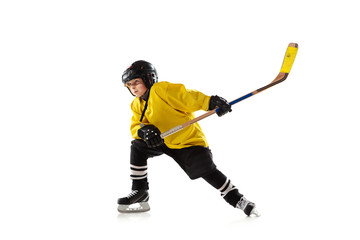 Little hockey player with the stick on ice court and white studio background. Sportsboy wearing equipment and helmet practicing, training. Concept of sport, healthy lifestyle, motion, movement, action