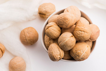 Walnuts in a white ceramic bowl on a white background