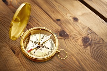 Old style brass compass on wooden desk