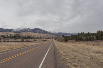 Fototapeta na wymiar Empty roadway leading to a snow capped mountain range