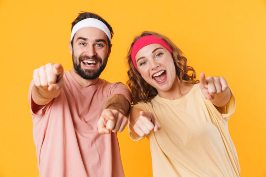 Portrait of athletic couple wearing headband smiling and pointing fingers