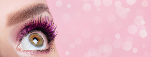 Trendy makeup banner. Female eye closeup on a pink background with bokeh and copy space