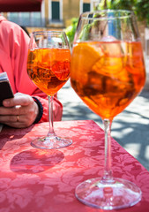 A glass with bright orange liquid, ice and a slice of orange, Spritz Aperol cocktail