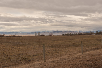 Two large silos sit at the back of a vast pasture with cattle fencing © Richard