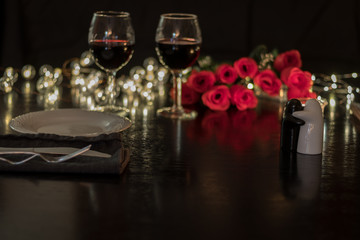 Red wine and roses on dark table for romantic dinner date night 