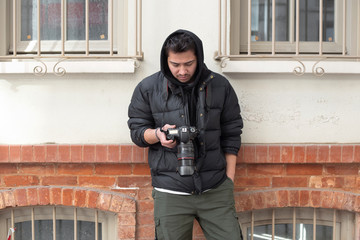 Young photographer looking at his photos on the street - obrazy, fototapety, plakaty