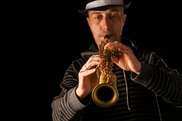 soprano saxophone in the hands of a guy on a black background