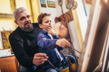 Father and son working and painting together in art studio