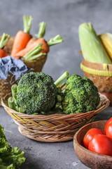Photo of fresh broccoli around vegetables on cutting board. Raw Picture. Gray background. Image.