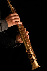 soprano saxophone in the hands of a guy on a black background