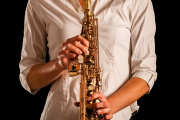Fototapeta premium soprano saxophone in the hands of a girl on a black background