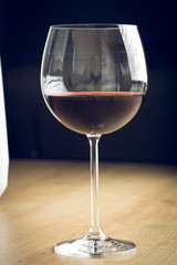 Red wine on a wineglass on a wooden surface isolated on a black background