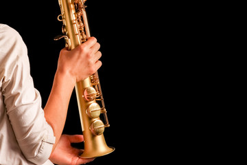 soprano saxophone in the hands of a girl on a black background