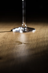 Water drops on a wooden table with blurry wineglass foot on a black background