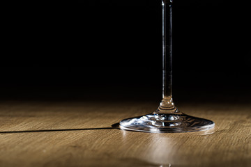 Wineglass foot shining on a wooden plank surface isolated on a black background