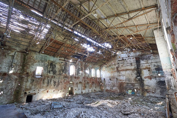 An abandoned, destroyed old factory with holes in the walls and roof.