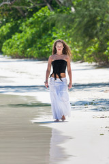 Fototapeta na wymiar young woman walks along the beach