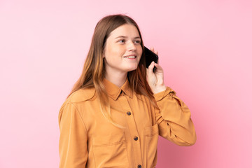 Ukrainian teenager girl over isolated pink background keeping a conversation with the mobile phone