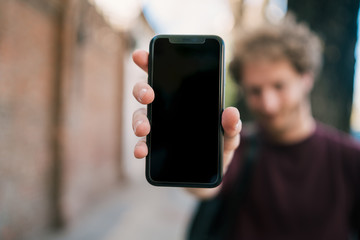 Young man showing blank smartphone screen.