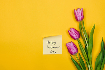 beauty of march. purple tulips and sticky note over yellow background. happy women's day