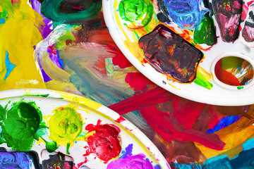 Art palette with paints, against colorful background