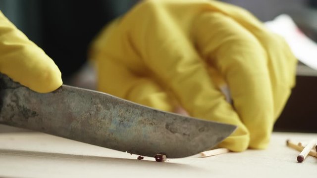 Men's hands in yellow gloves cut off heads with sulfur in matches. CU Side view