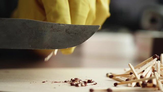 Men's hands in yellow gloves cut off heads with sulfur in matches. CU Side view