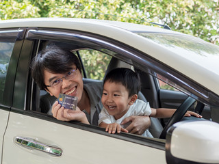 Asian little child boy and father inside car with happy smiling face, dad holding credit card.