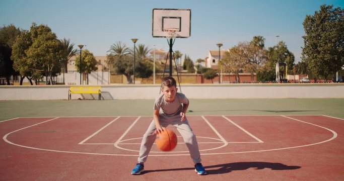Cute kid hiting a basketball ball. Boy practicing shooting a basketball.