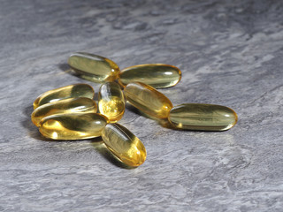 Many capsules Omega 3 on a gray stone background. Health care concept