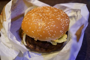 Close-up of man holding eating fastfood cheeseburger  