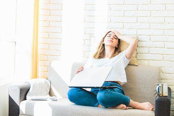 young attractive woman at home tiredly seeking for a job or rent in internet
