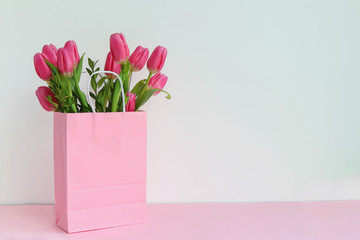 A bouquet of pink tulips in a pink paper bag, space for text