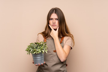 Ukrainian teenager gardener girl holding a plant thinking an idea